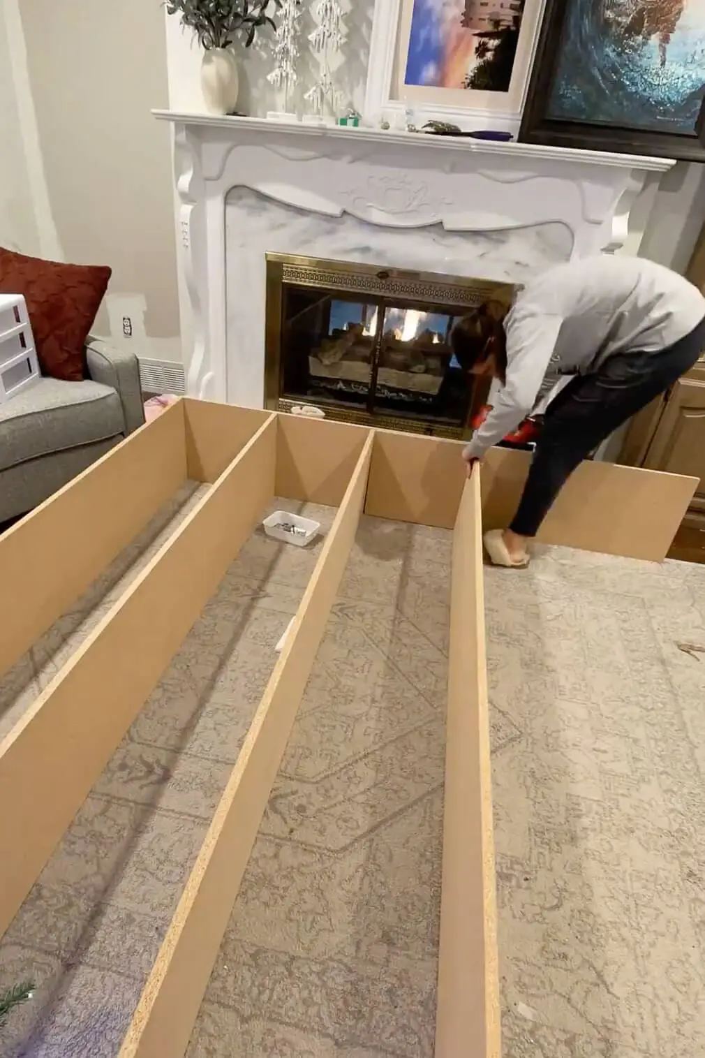 Securing MDF panels together to create a sturdy frame for a custom built-in unit. The structure is laid out on a carpeted floor.